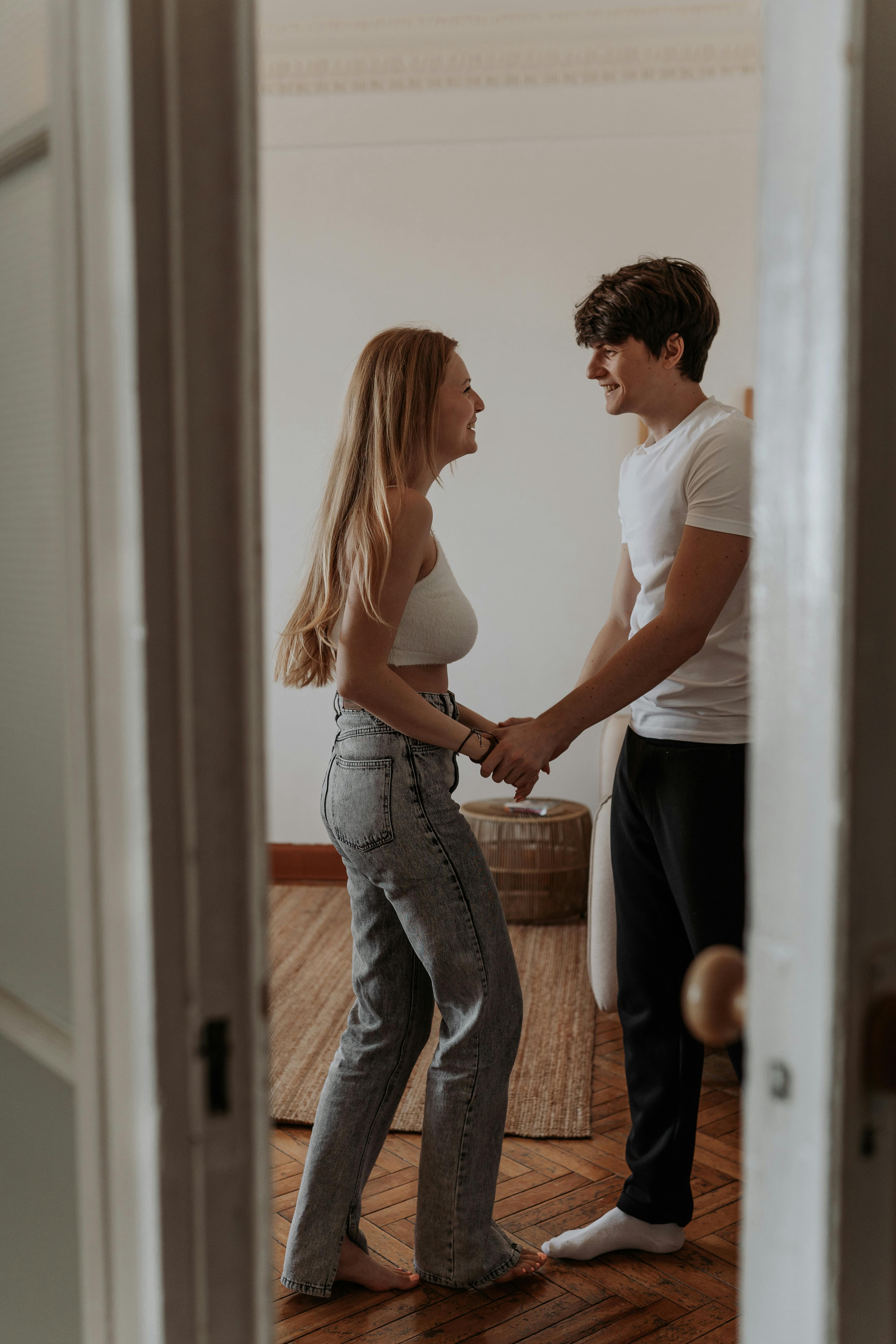 A young couple shares a romantic moment holding hands in a cozy home setting.