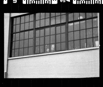 Black and white shot of a factory window capturing a serene indoor moment.