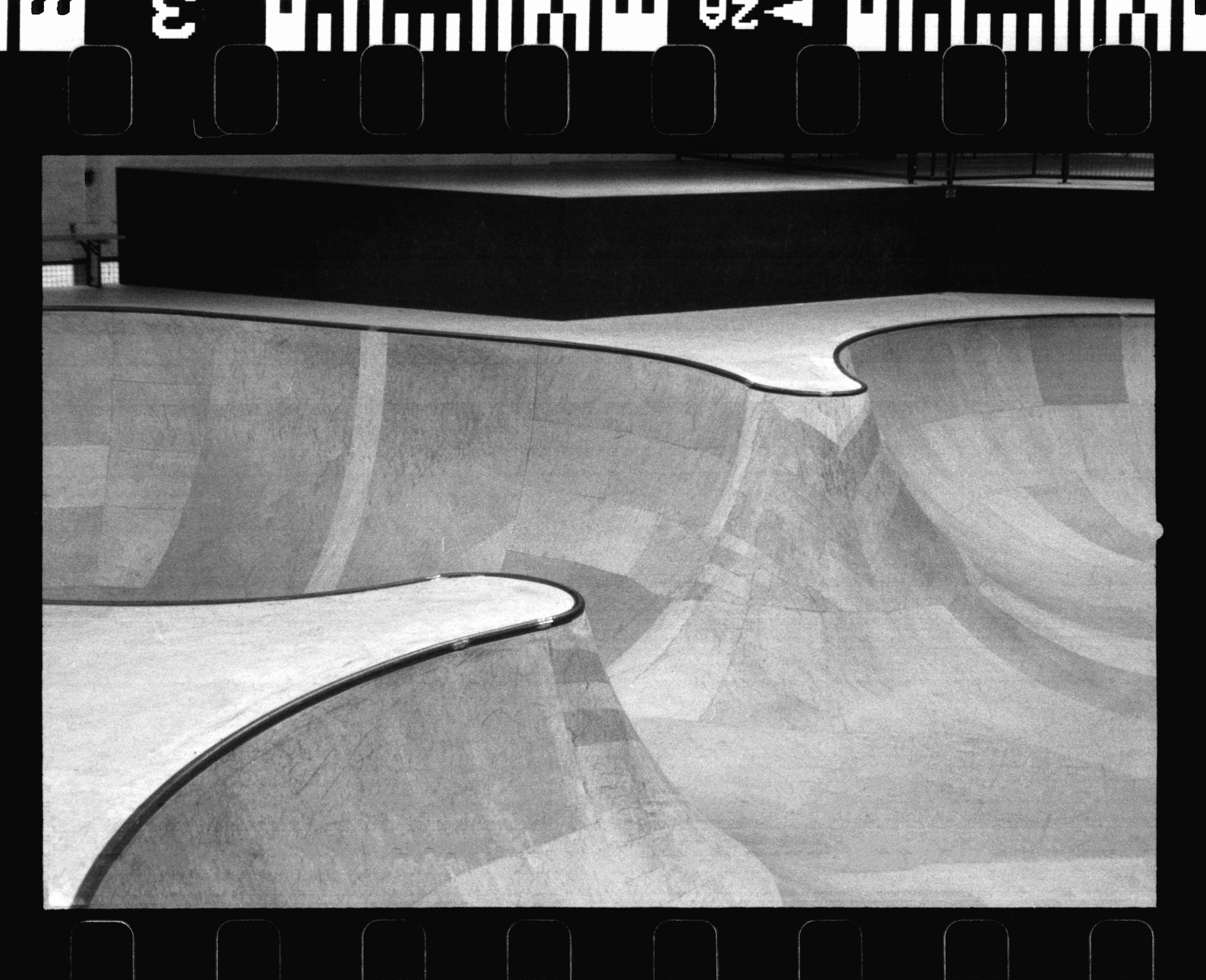 Grayscale image of an empty skate park with smooth curves and concrete textures.