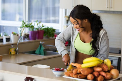 Woman Standing on Kitchen About to Sliced Potato