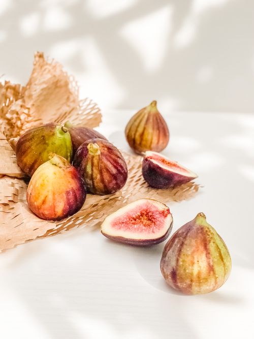 Free A collection of fresh, ripe figs displayed elegantly in natural sunlight, evoking a sense of summer. Stock Photo
