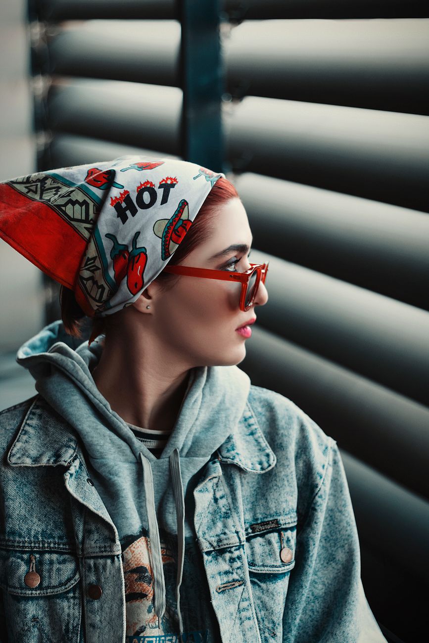 Portrait of a fashionable woman in Tehran wearing a colorful bandana, sunglasses, and denim jacket.