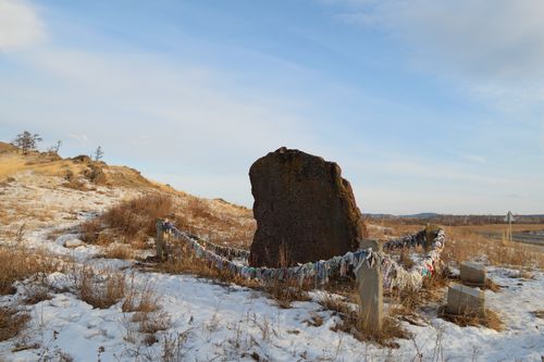 Free Stone monument adorned with colorful fabric in a snowy winter field. Stock Photo