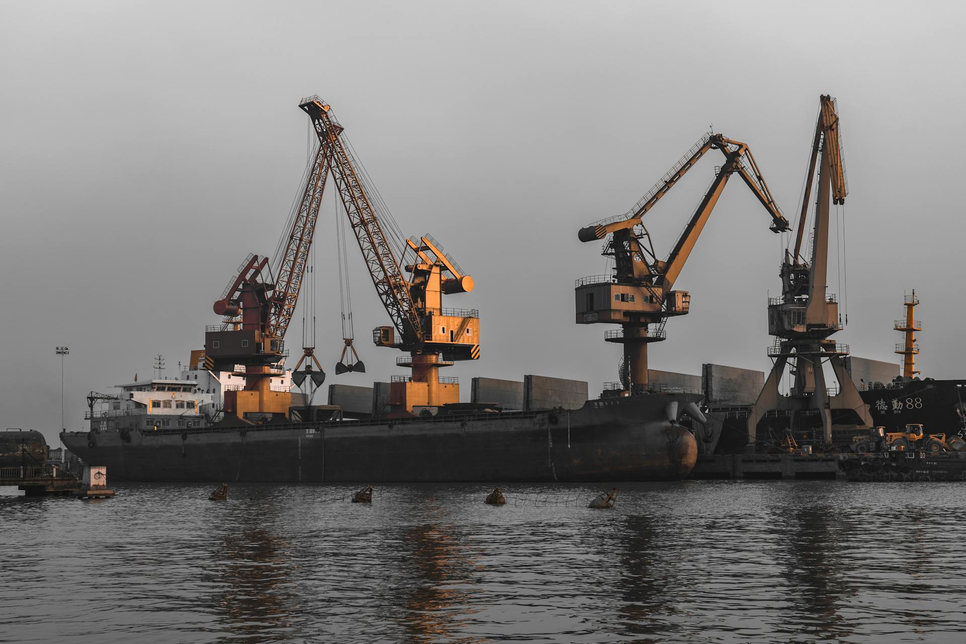 Cargo ship docked at a port with large cranes, showcasing industrial logistics operations.
