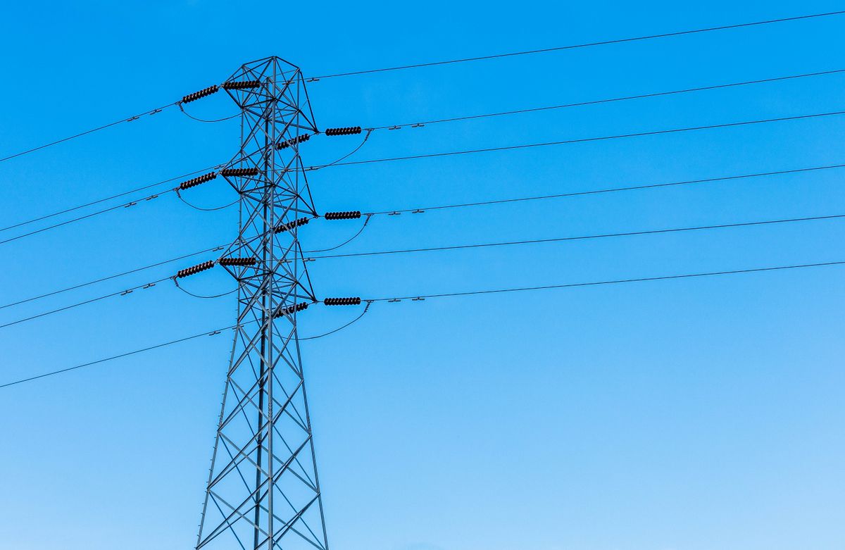High-voltage transmission tower with power lines under a bright blue sky