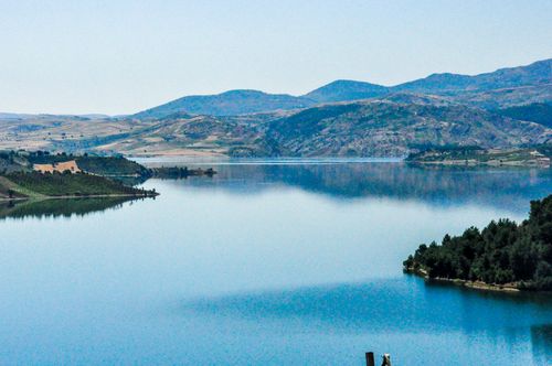 Free Tranquil lake setting with mountain reflections, clear sky, and verdant landscape. Stock Photo