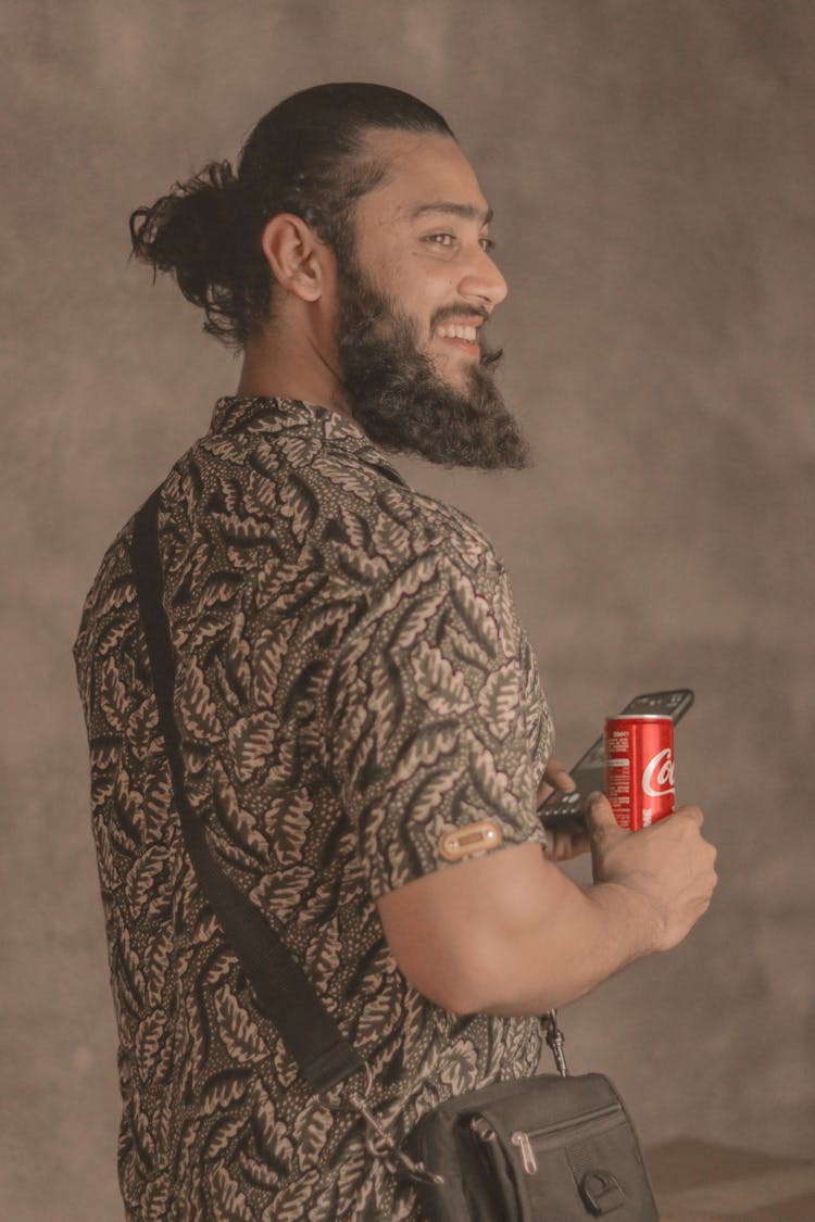 Man In Brown Printed Shirt Holding A Smartphone And A Can Of Softdrrinks