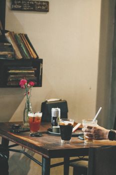 Cozy indoor cafe scene with diverse drinks and books on a wooden table.