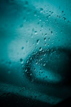 Close-up of raindrops on a window creating a moody abstract pattern.