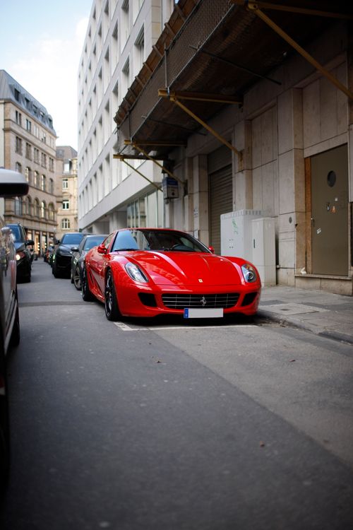 Free A sleek red sports car parked on a bustling city street, showcasing luxury and style. Stock Photo