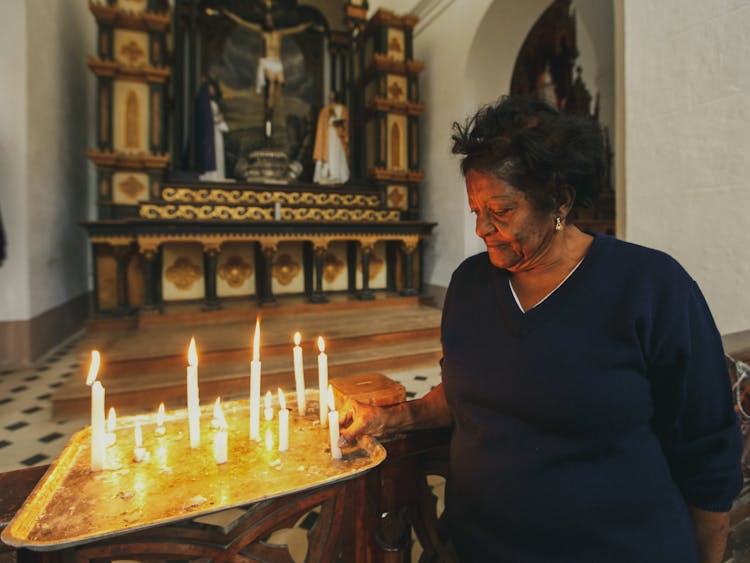 Elderly Woman Lighting Candle In Church