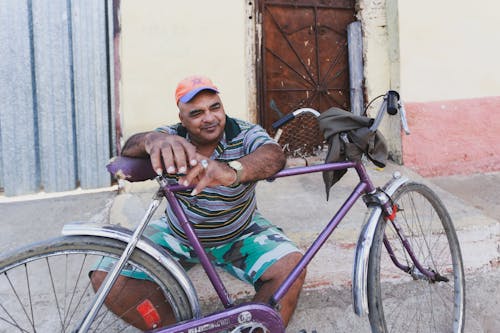 A Man Leaning on Purple Bicycle