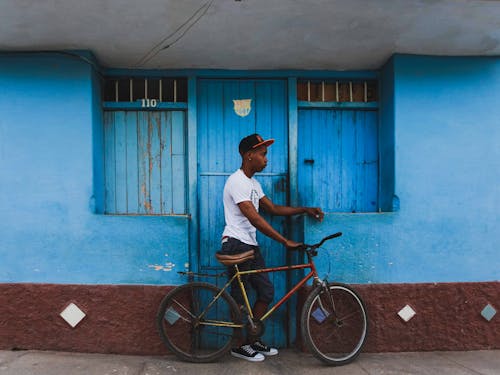 Man with Bicycle Standing under Blue Wall