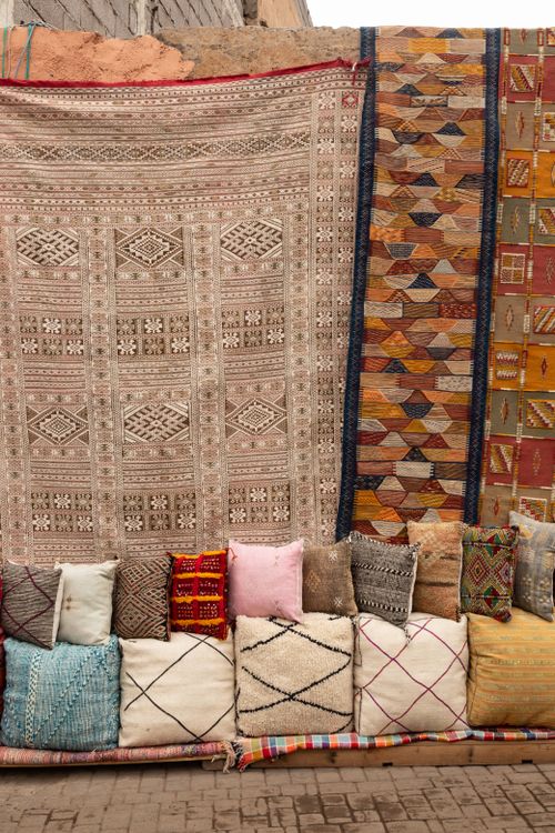 Free A vibrant collection of handwoven traditional rugs and cushions on an outdoor display. Stock Photo