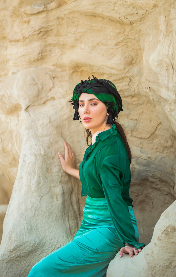 Woman In Green Outfit Sitting On Rock Formation