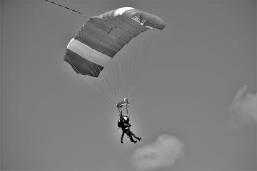 Two Persons in Parachutes Gliding in Sky