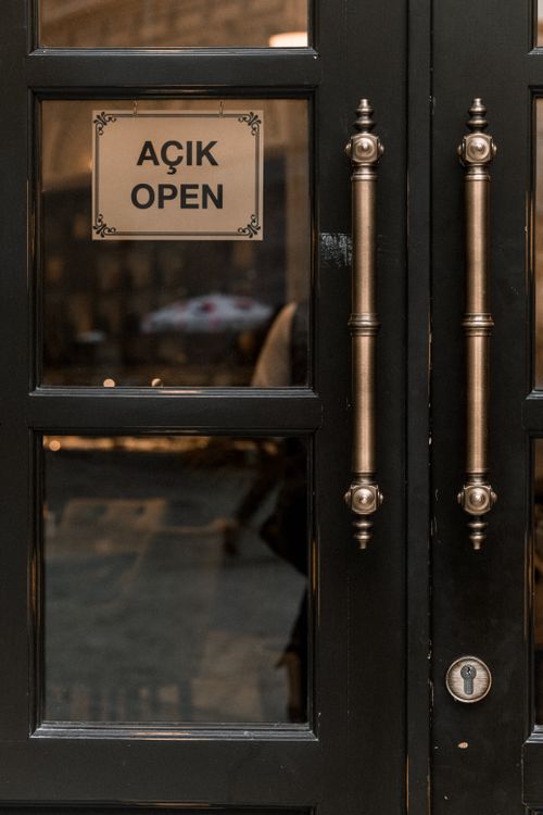 Free Close-up view of double doors with an 'Açık Open' text sign, reflecting a cozy street. Stock Photo