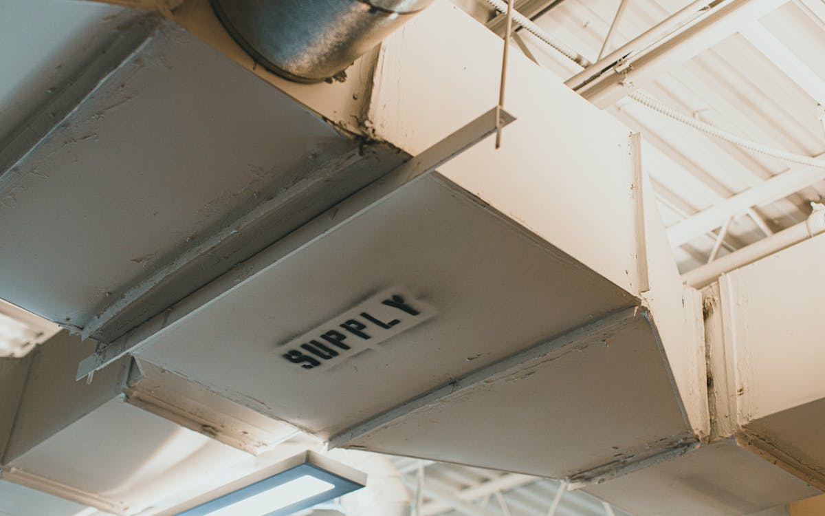 Close-up view of an air duct labeled 'SUPPLY' in an industrial setting.