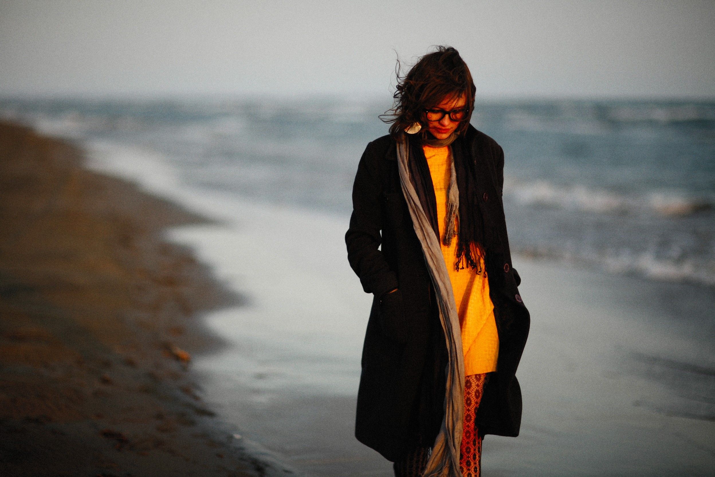 A Woman in Black Coat Walking on Beach · Free Stock Photo