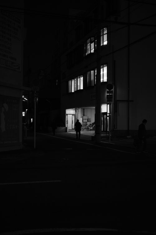 Free A silhouette of a person walking at night in an urban street scene. Stock Photo