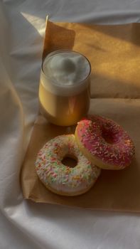 Delicious latte and colorful sprinkle doughnuts on brown paper, perfect for breakfast moments.