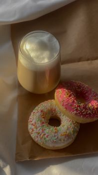 A cozy top view of two sprinkled donuts paired with a refreshing glass of iced coffee.
