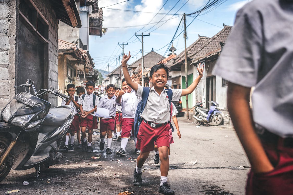 Boy in White and Red School Uniform Raising Hands Outdoors