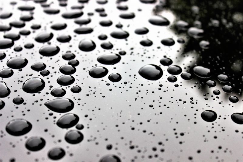Macro de gouttes d'eau sur surface noire réfléchissante
