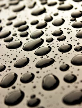 Close-up of glossy water droplets on a smooth, reflective surface creating a mesmerizing pattern.