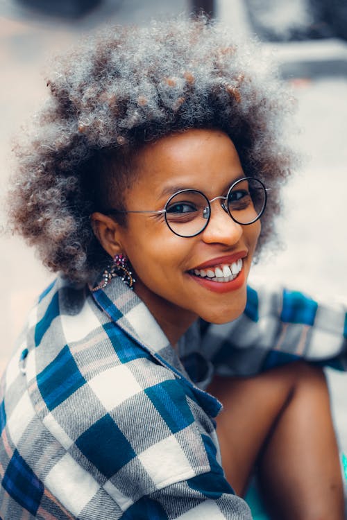 A Smiling Woman Wearing a Plaid Shirt and Eyeglasses