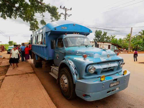 Free A rustic blue bus, used as public transport, stands on a street with people boarding and alighting. Stock Photo