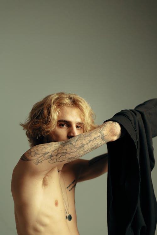 Blond Man with Tattoos Taking Shirt Off