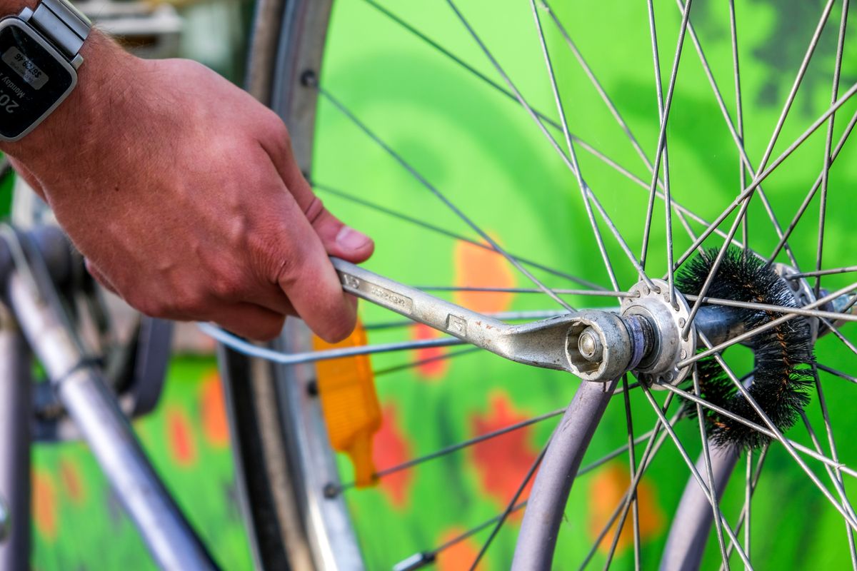 Close-up of a bicycle wheel being inspected with a hand tool