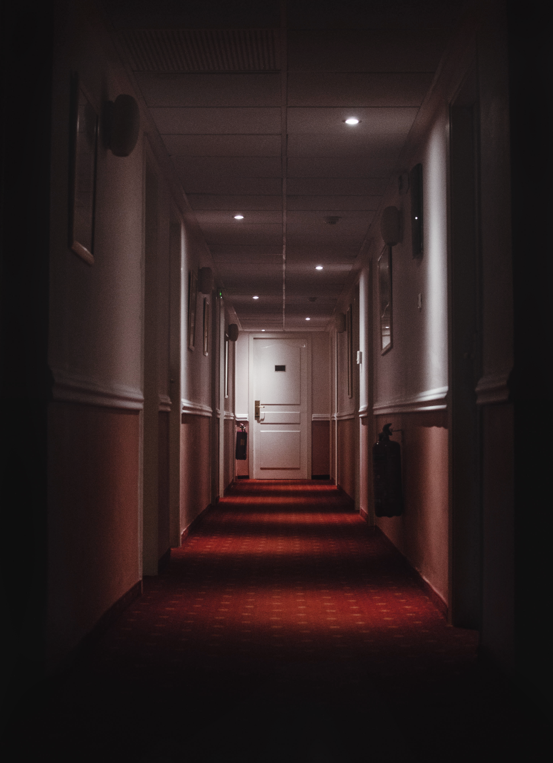 A dark, atmospheric hotel hallway with elegant interior design and rich red carpet