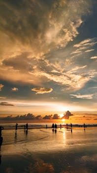 A breathtaking view of a beach sunset with silhouettes of people walking along the shore, creating a serene and picturesque scene.