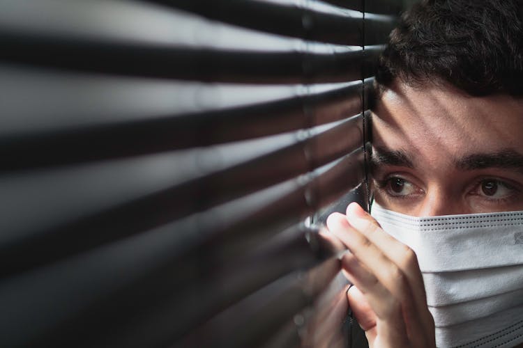 Close Up Photo Of A Man Peeking From Blinds