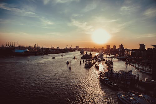 A breathtaking view of Hamburg harbor at sunset, with boats and skyline silhouetted.