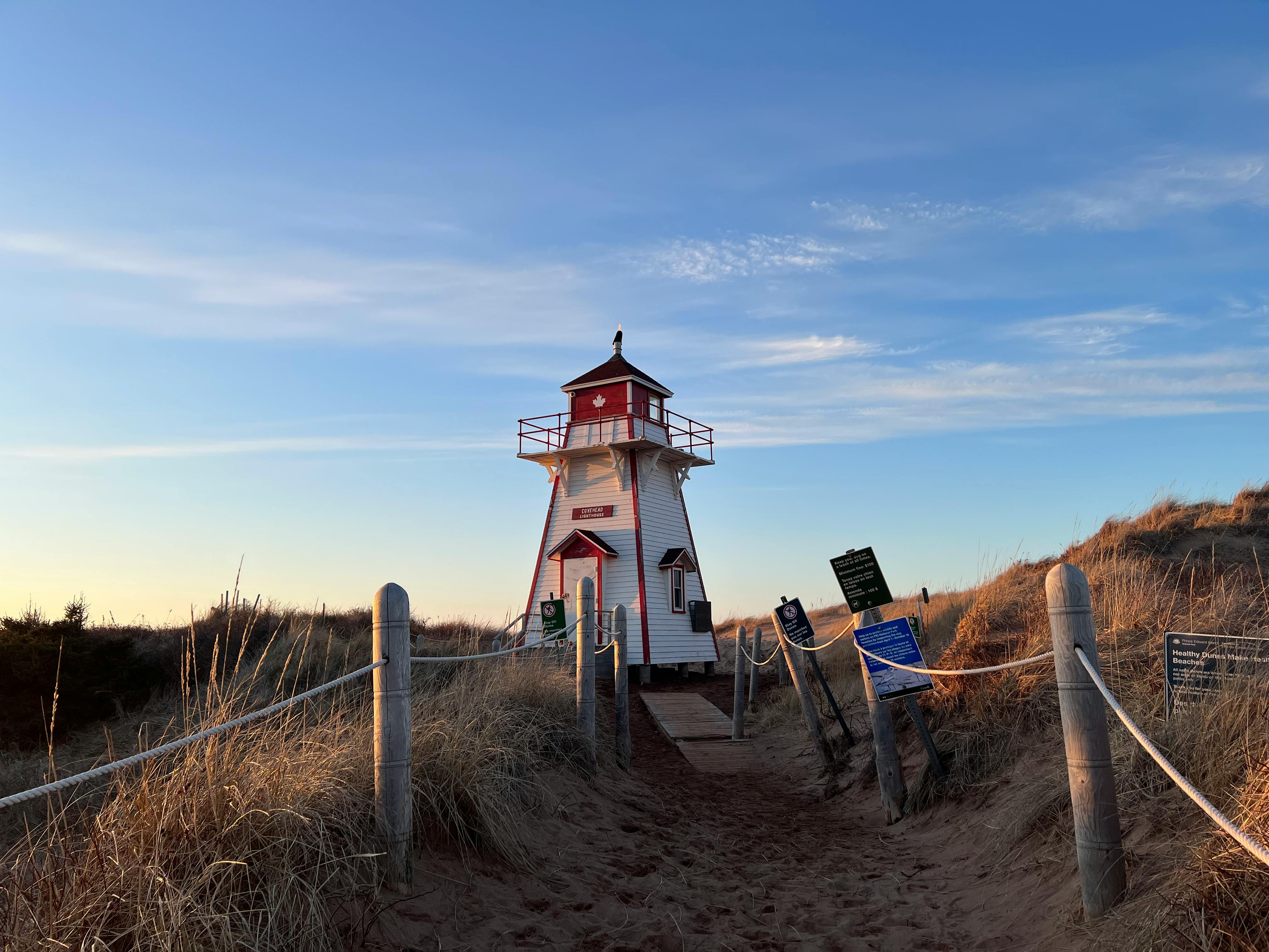 white and red lighthouse on brown field under the blue sky