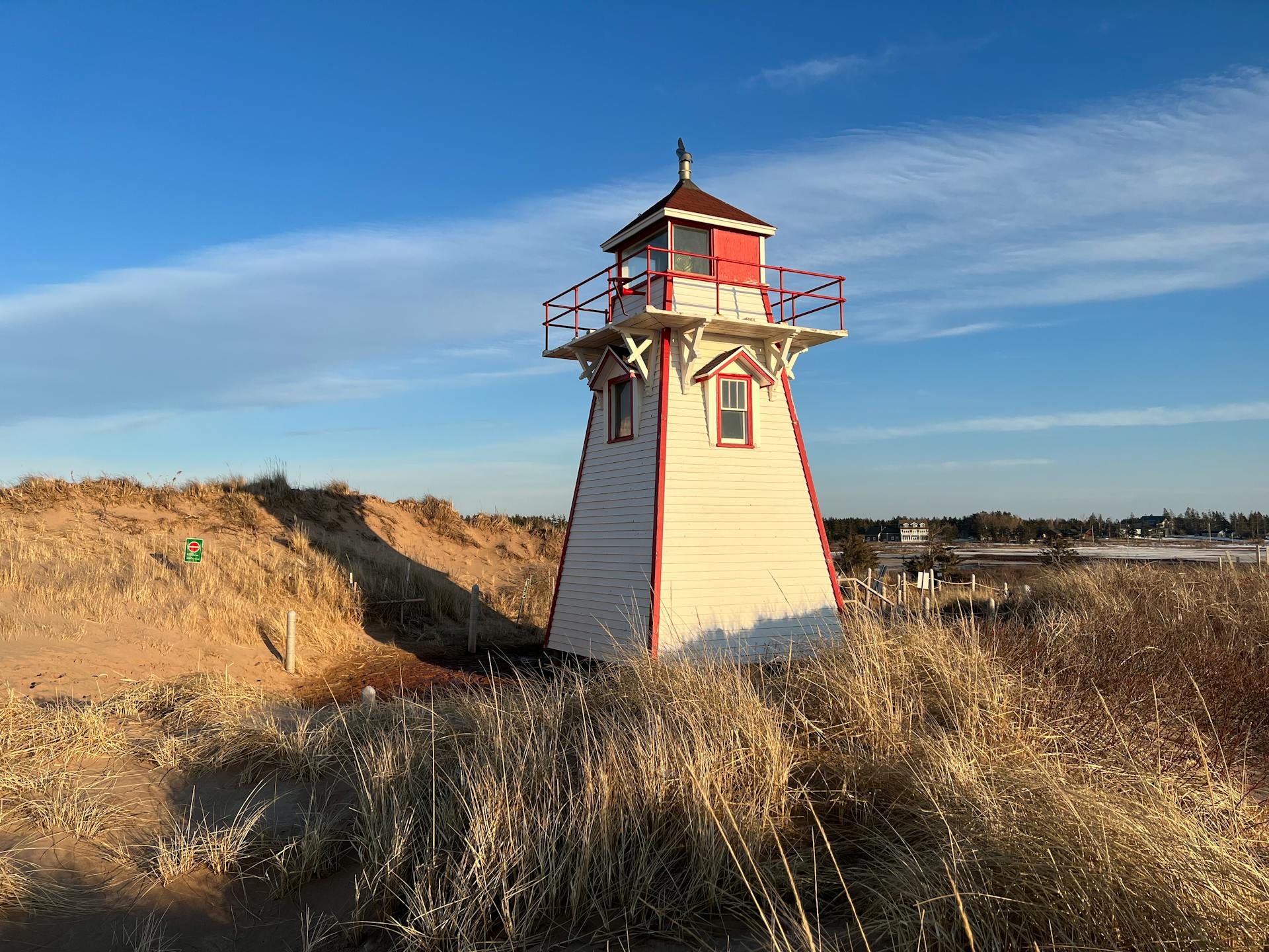 Rustic Covehead Harbour Lighthouse in Prince Edward Island, surrounded by dunes under a clear sky.