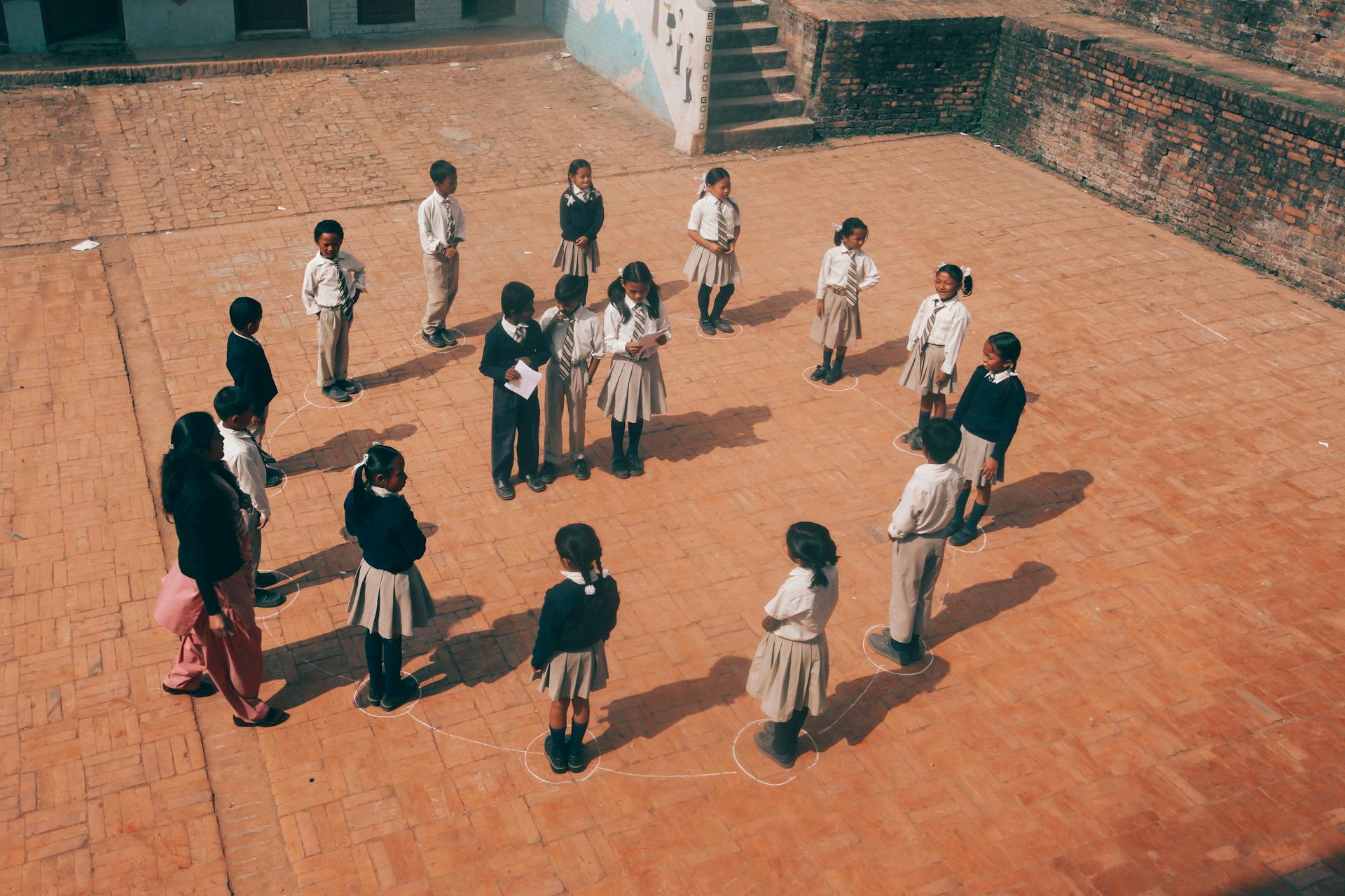 A top-down view of children in uniform engaging in a group activity in a school courtyard.