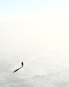 A lone person walking across an expansive, sunlit field in Saint Petersburg, Russia.