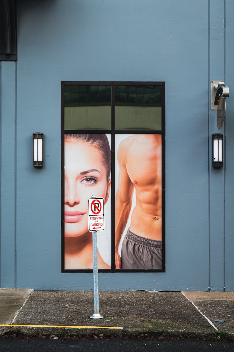 A Poster Of A Woman And A Man On The Wall Of The Sidewalk