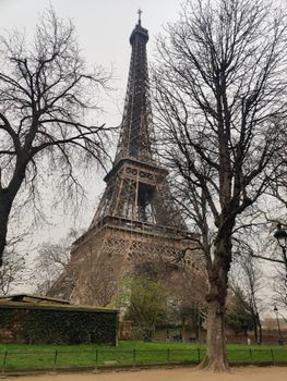 Iconic Eiffel Tower framed by bare trees in Paris during early spring.