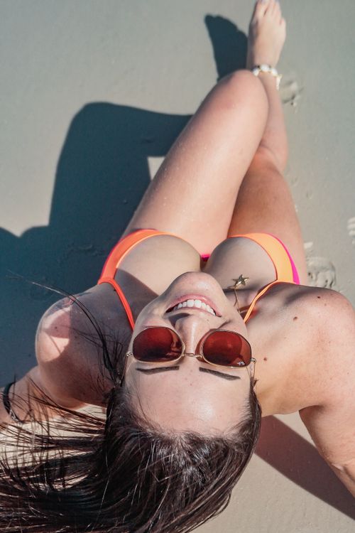 Free Happy woman in bikini with sunglasses smiling on sandy beach from top view. Stock Photo