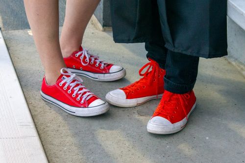 Free Two pairs of red sneakers on concrete, symbolizing casual fashion and friendship. Stock Photo