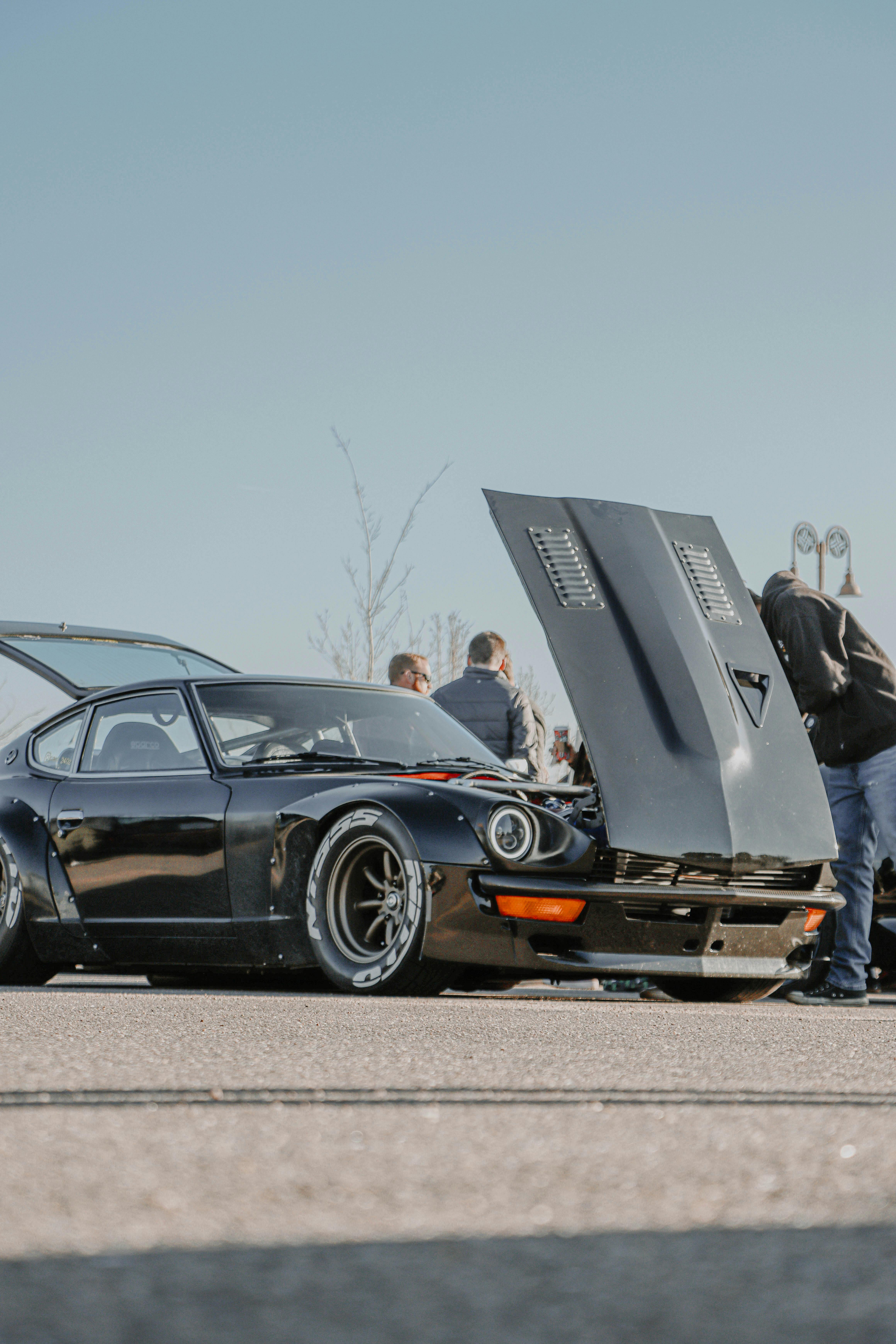 nissan fairlady z with a raised hood parked on a parking lot at a car meet