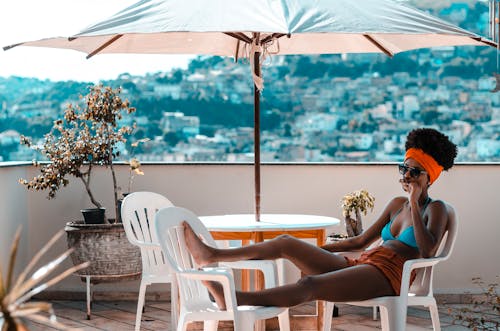 Free Woman Sitting on Armchair Under White Patio Umbrella Stock Photo