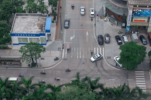 Aerial view of a busy urban intersection with vehicles and pedestrians in a city setting.