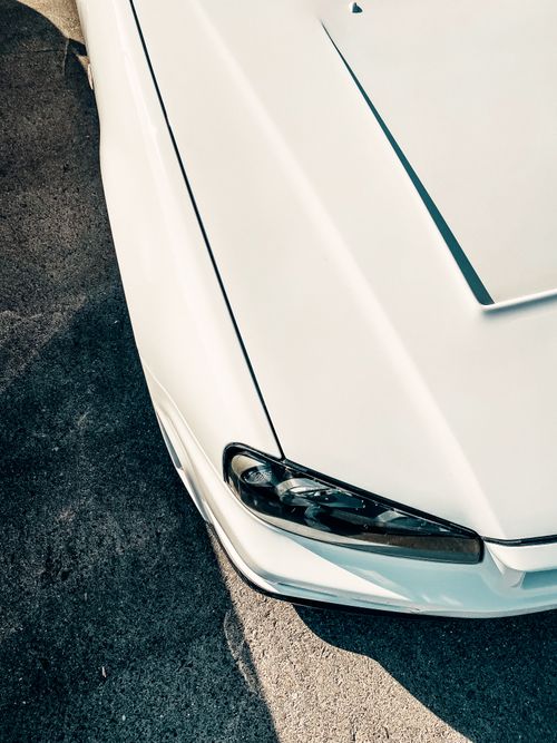 Free A vertical shot of a sleek white sports car on rough asphalt, showing modern design. Stock Photo