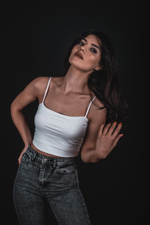 Free A fashionable young woman posing confidently against a dark background in a studio setting. Stock Photo